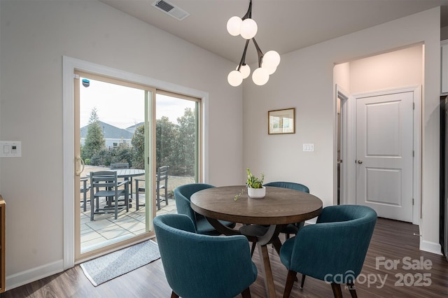 dining area with baseboards, wood finished floors, visible vents, and an inviting chandelier