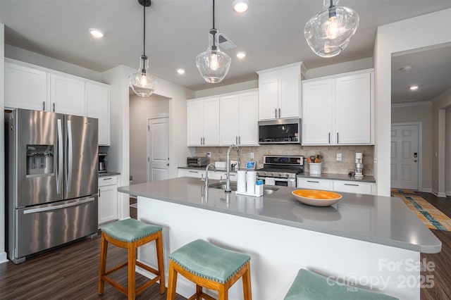 kitchen featuring an island with sink, white cabinetry, stainless steel appliances, and backsplash