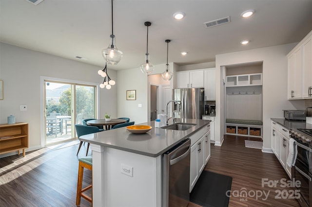 kitchen with a breakfast bar, a sink, visible vents, appliances with stainless steel finishes, and dark countertops