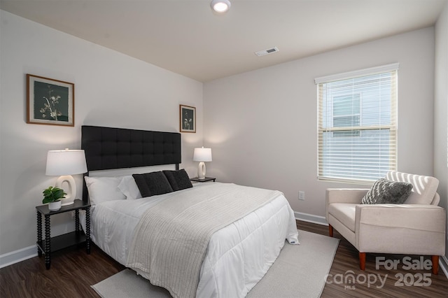 bedroom with baseboards, visible vents, and wood finished floors