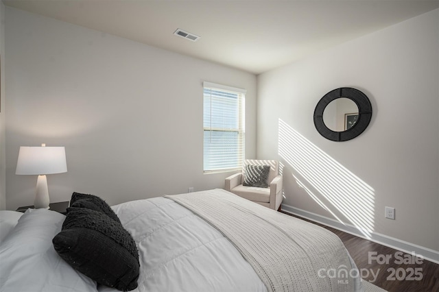 bedroom with dark wood-style floors, visible vents, and baseboards