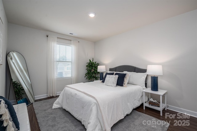 bedroom featuring wood finished floors, visible vents, and baseboards