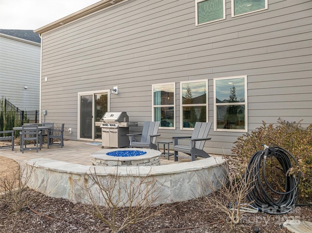 rear view of house featuring fence, a fire pit, and a patio