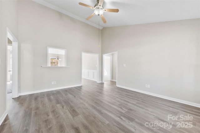 spare room with high vaulted ceiling, baseboards, a ceiling fan, and wood finished floors