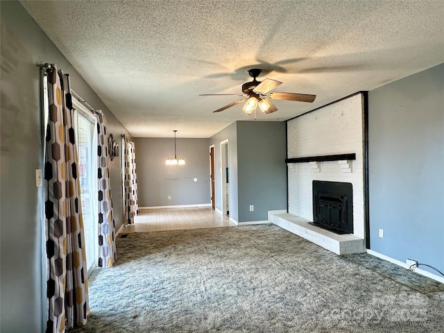 unfurnished living room with baseboards, ceiling fan, a textured ceiling, carpet flooring, and a brick fireplace