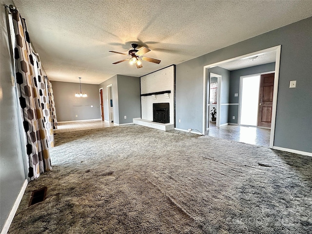 unfurnished living room featuring carpet floors, a fireplace, visible vents, and ceiling fan with notable chandelier