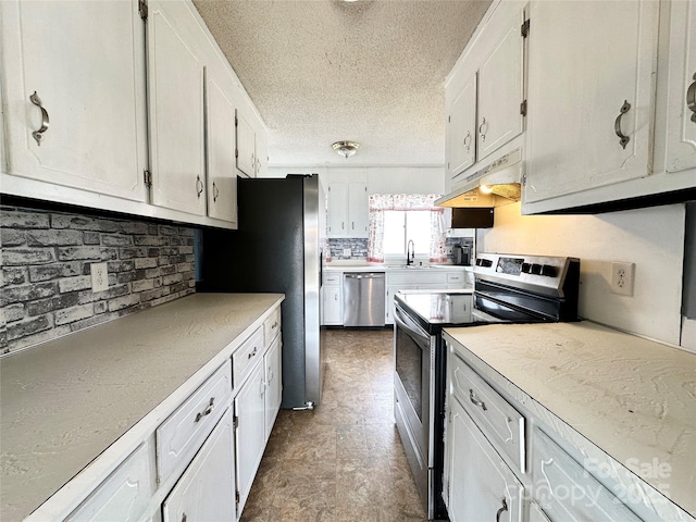 kitchen with a textured ceiling, under cabinet range hood, stainless steel appliances, a sink, and white cabinets