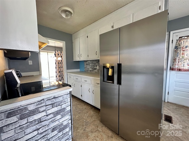 kitchen featuring light countertops, white cabinetry, stovetop, and stainless steel refrigerator with ice dispenser