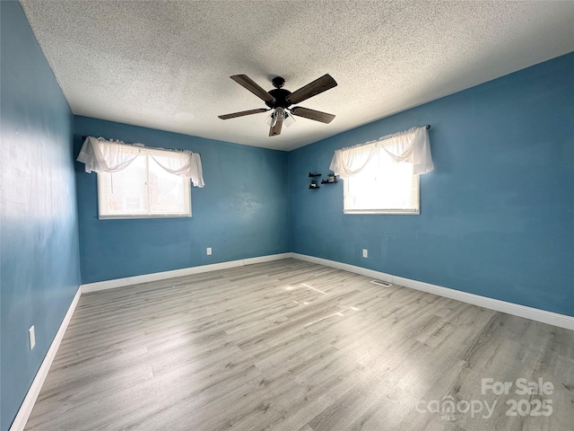 unfurnished room featuring ceiling fan, a textured ceiling, baseboards, and wood finished floors