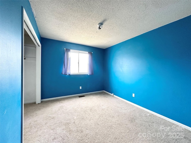 unfurnished bedroom with baseboards, visible vents, a textured ceiling, carpet flooring, and a closet