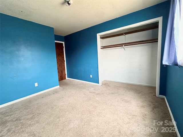 unfurnished bedroom with carpet floors, a closet, a textured ceiling, and baseboards