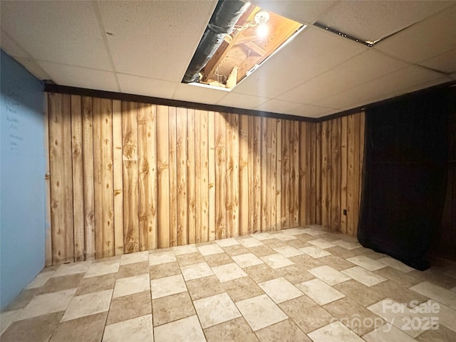 finished below grade area featuring wooden walls and a drop ceiling