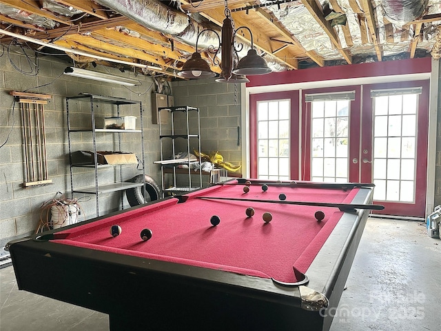 game room with concrete block wall, billiards, unfinished concrete floors, and french doors