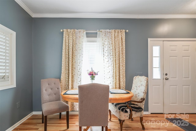 dining space featuring light wood-style floors, ornamental molding, and baseboards