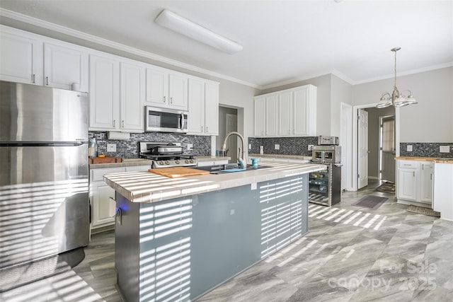 kitchen with stainless steel appliances, light countertops, white cabinets, and crown molding