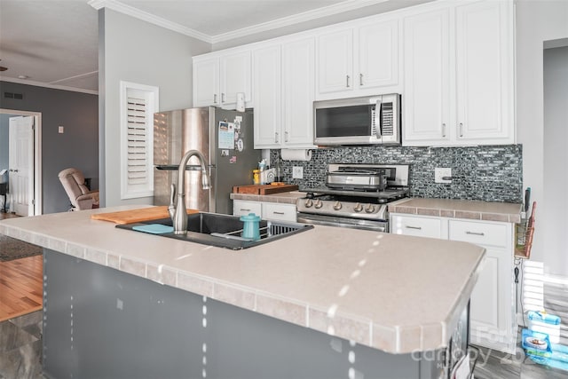 kitchen featuring crown molding, stainless steel appliances, light countertops, backsplash, and white cabinets