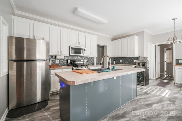 kitchen featuring white cabinetry, light countertops, ornamental molding, appliances with stainless steel finishes, and tasteful backsplash