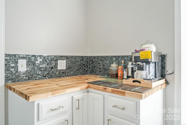 kitchen with wood counters, white cabinets, and backsplash