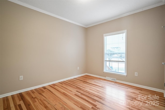 empty room featuring light wood-style floors, baseboards, visible vents, and ornamental molding