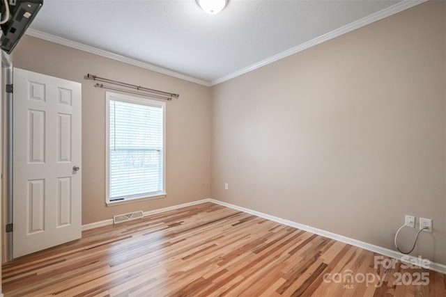 unfurnished room with light wood finished floors, visible vents, and ornamental molding