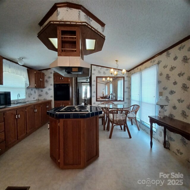 kitchen with tile countertops, appliances with stainless steel finishes, vaulted ceiling, a sink, and wallpapered walls