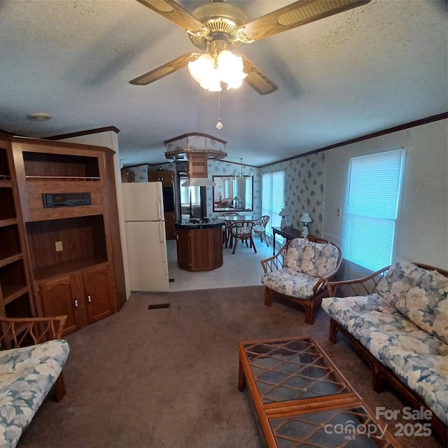 living area with ornamental molding, light colored carpet, a textured ceiling, and a ceiling fan