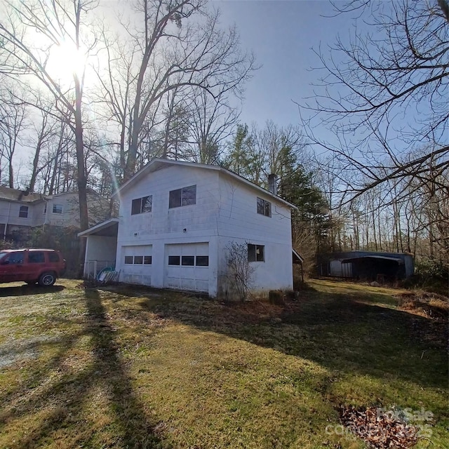 view of property exterior featuring driveway, an attached garage, a chimney, and an outbuilding