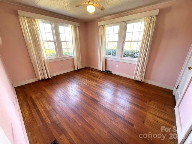 spare room featuring hardwood / wood-style flooring, plenty of natural light, visible vents, and baseboards