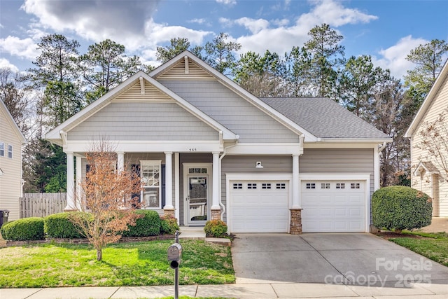 view of front of house with an attached garage, fence, driveway, roof with shingles, and a front lawn