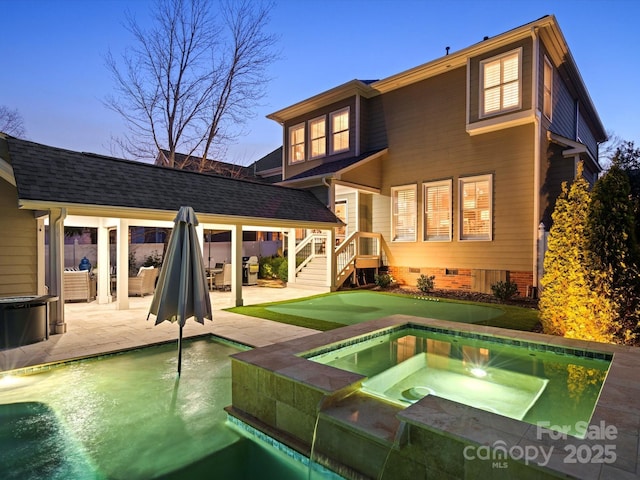 rear view of house with an in ground hot tub, crawl space, a patio area, and an outdoor pool