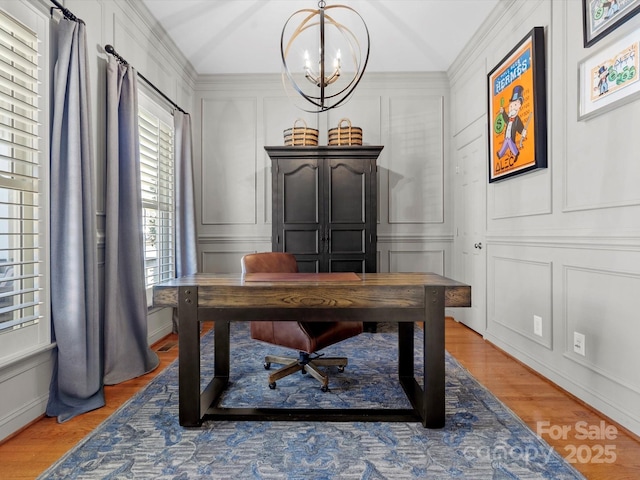 office space with an inviting chandelier, light wood-style flooring, and a decorative wall