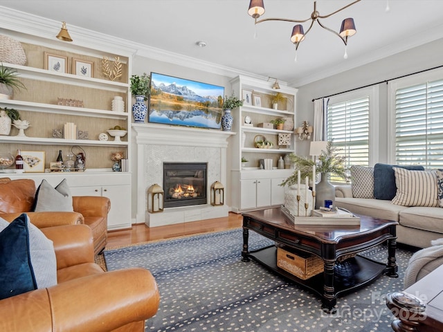 living area with a glass covered fireplace, a notable chandelier, crown molding, and wood finished floors