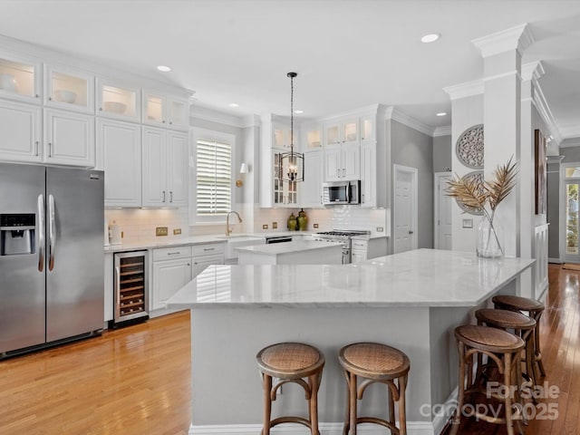 kitchen featuring appliances with stainless steel finishes, wine cooler, light wood-style floors, and a center island