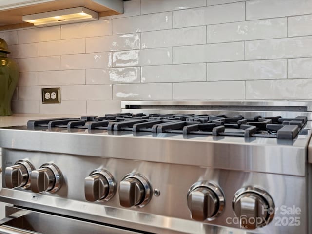 room details with gas stove, light countertops, and backsplash