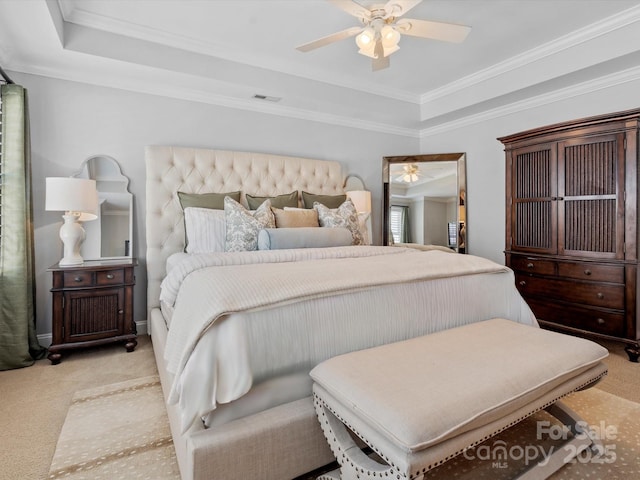 bedroom with a tray ceiling, light colored carpet, and visible vents