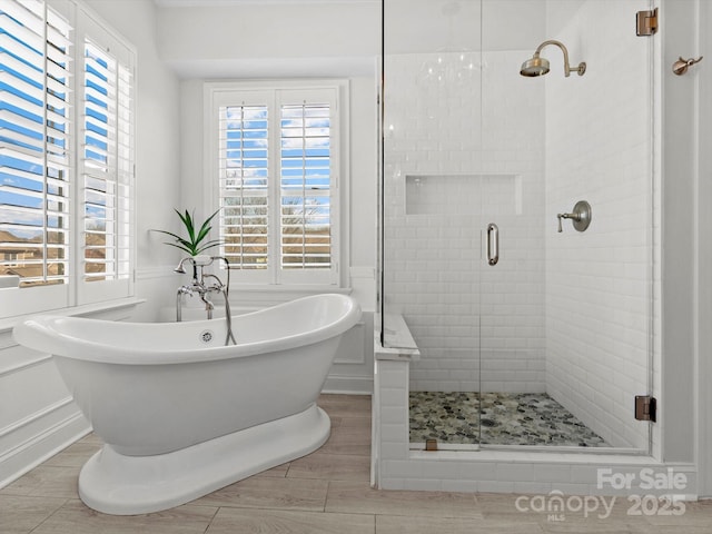 bathroom with wood tiled floor, a freestanding bath, and a shower stall