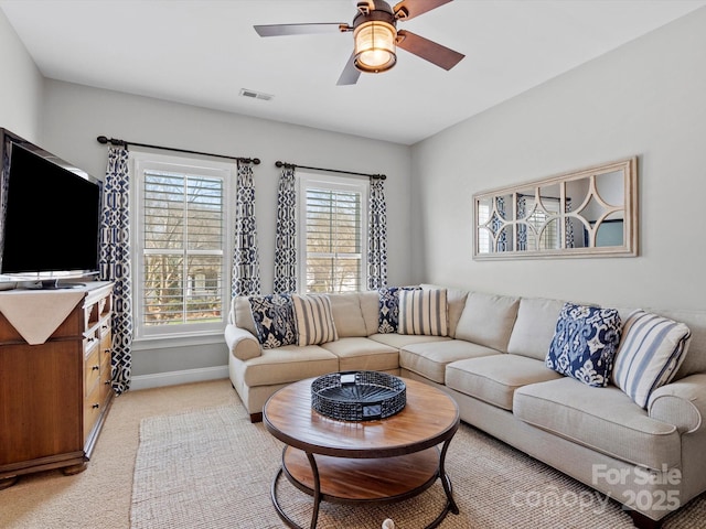 living room with light colored carpet, visible vents, ceiling fan, and baseboards