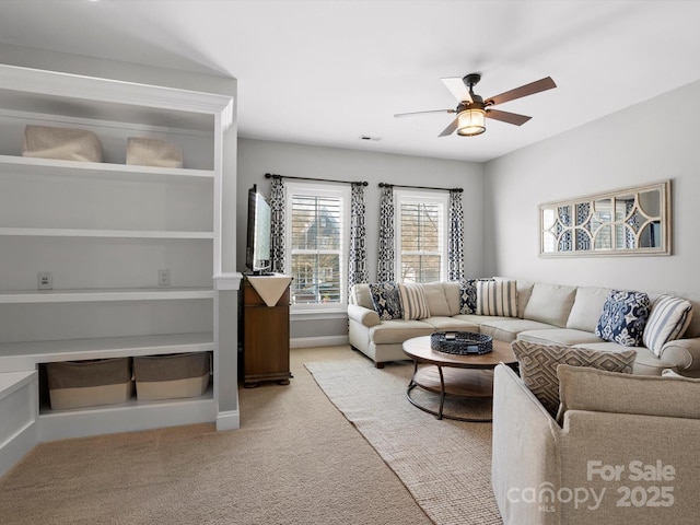 living area with light carpet, baseboards, and a ceiling fan