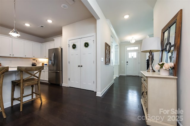 kitchen with dark wood-style floors, stainless steel refrigerator with ice dispenser, recessed lighting, white cabinetry, and baseboards