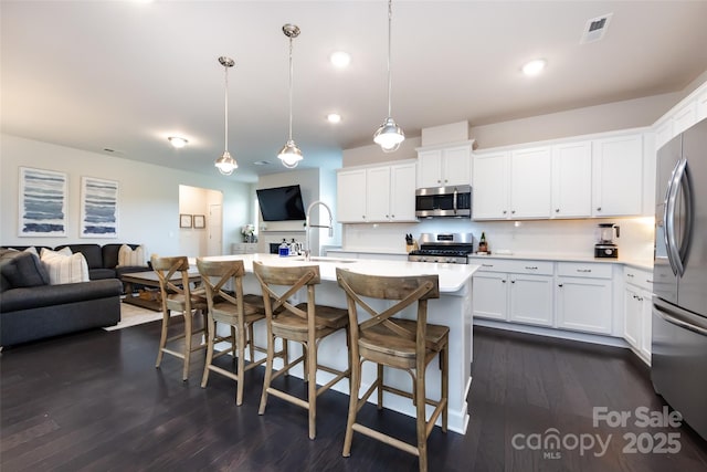 kitchen with stainless steel appliances, dark wood-type flooring, a sink, open floor plan, and light countertops