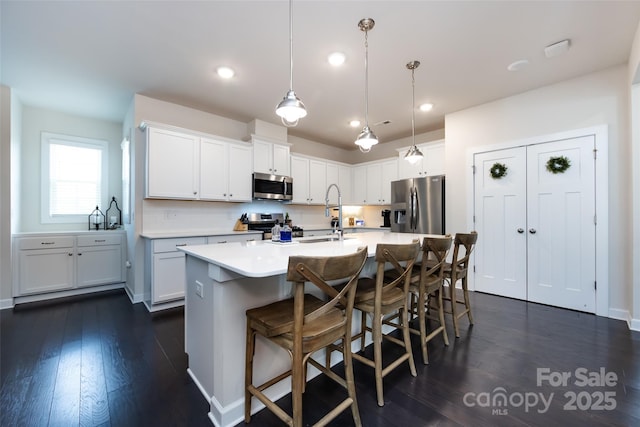 kitchen with dark wood-style floors, appliances with stainless steel finishes, light countertops, white cabinetry, and a sink