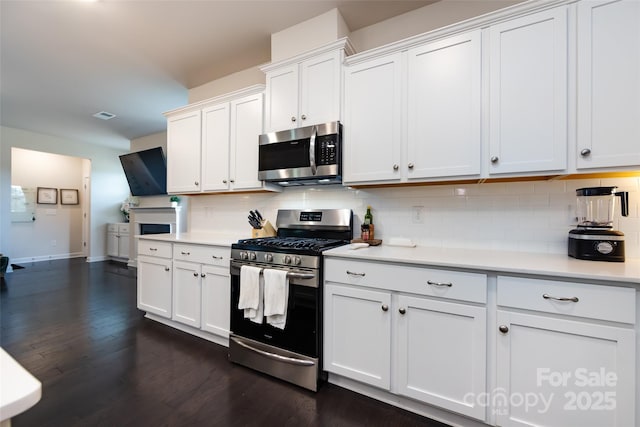 kitchen with white cabinetry, decorative backsplash, stainless steel appliances, and light countertops