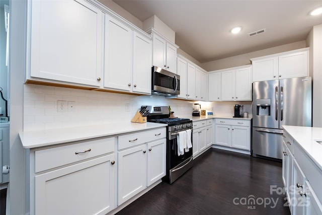 kitchen with stainless steel appliances, visible vents, white cabinets, light countertops, and backsplash