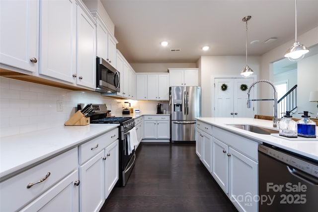 kitchen with stainless steel appliances, tasteful backsplash, light countertops, white cabinetry, and a sink