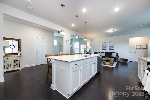 kitchen with white cabinets, dark wood finished floors, open floor plan, light countertops, and stainless steel dishwasher