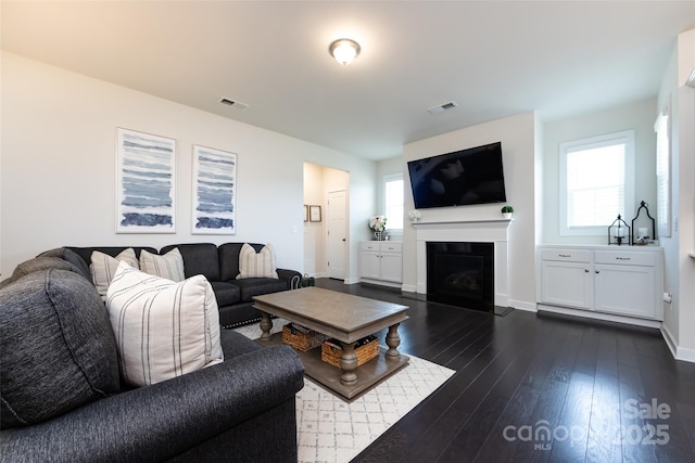 living area with visible vents, dark wood finished floors, and a wealth of natural light