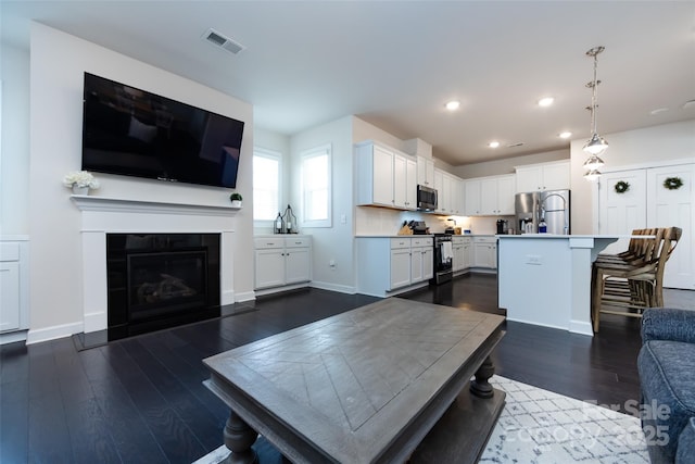 living room with a tile fireplace, recessed lighting, visible vents, baseboards, and dark wood finished floors