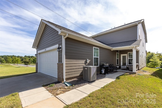 exterior space with a garage, central AC unit, and a lawn