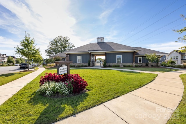 view of front facade with roof with shingles and a front yard