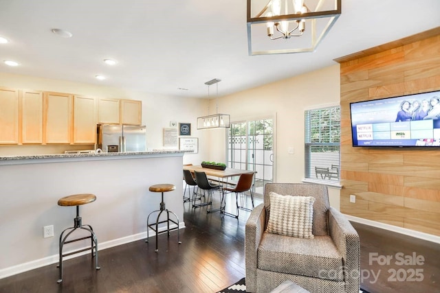 kitchen featuring dark wood finished floors, stainless steel fridge with ice dispenser, a kitchen breakfast bar, light brown cabinets, and recessed lighting